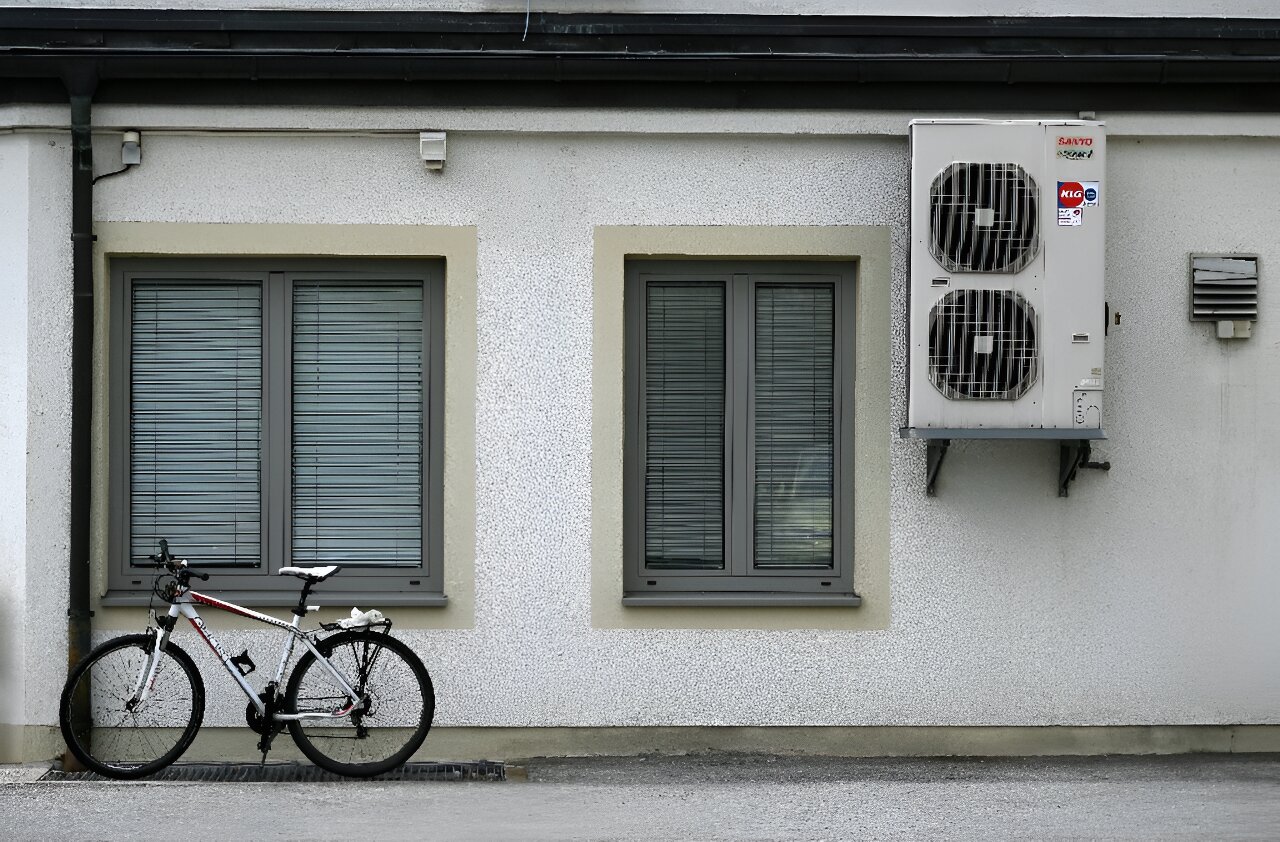 kondensat spływający z jednostki klimatyzatora na trawę pod wysokim blokiem mieszkalnym