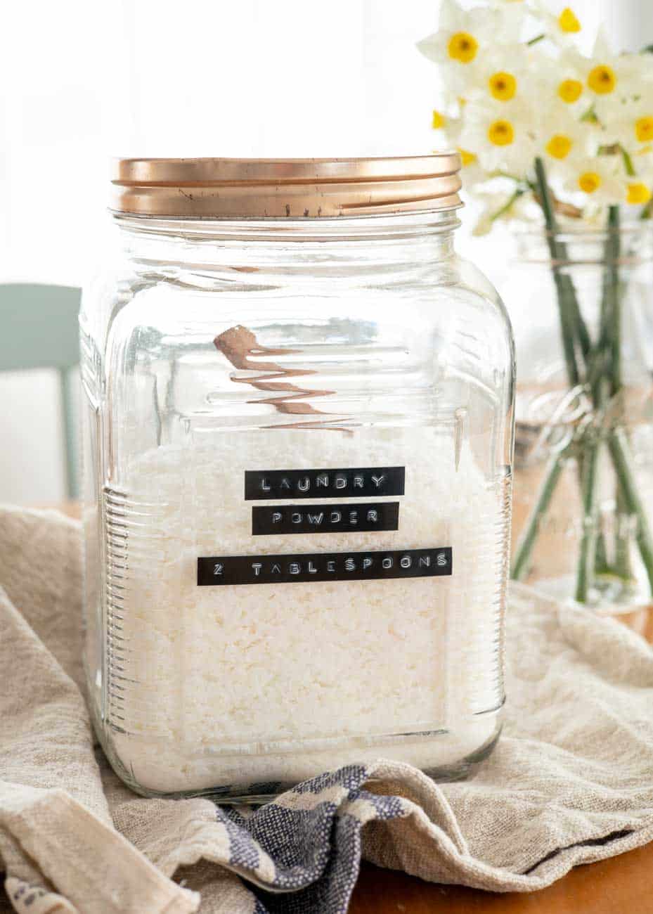 szklany słoik z białym proszkiem otoczony sodą mydłem i boraksem na stole