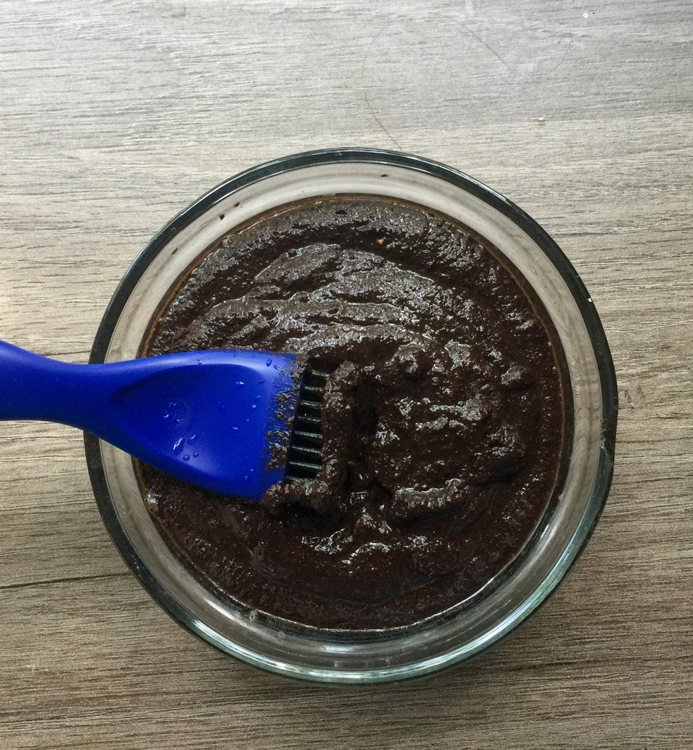 Głęboki zielony proszek henny w glinianej misce obok świeżej wody